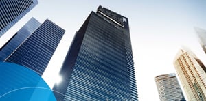 Low-angle view of modern glass skyscrapers in a financial district under a clear sky.