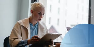 A blonde lady sitting and looking at an iPad