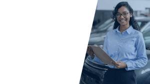 A woman with a clipboard, standing in front of a car in a car dealership