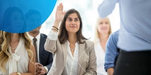 Woman sitting in a crowd and raising her hand