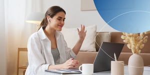 Lady sitting at a table waving at laptop