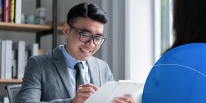 Man wearing suit looking at paper and smiling 