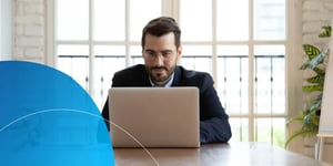 Man sitting at desk looking into laptop 