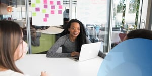 3 women sitting at a table in the office talking 