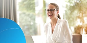 Confident sales professional smiling at her laptop in a sunlit office, with a Retorio brand overlay on the lower-left