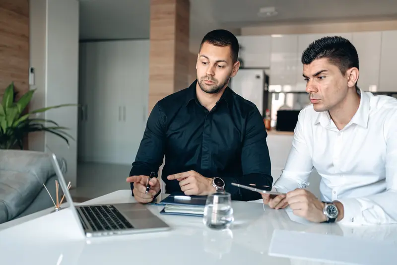 Two male employees looking at laptop screen during training